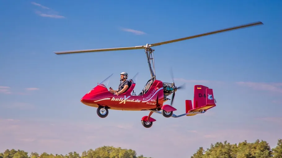 Red helicopter flying over a forest area.