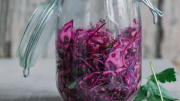 Jar of fermented red cabbage on table.