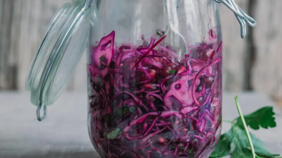 Glas mit fermentiertem Rotkohl auf Tisch.