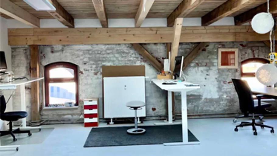 Büro mit Holzbalken und minimalen Möbeln.