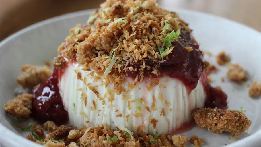 Dessert topped with fruit and crumble on plate.