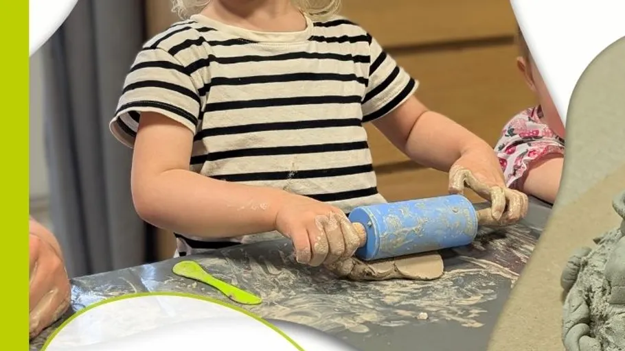 Kind rollt Ton mit blauem Roller drinnen.
