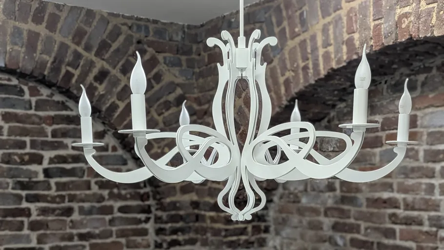 White chandelier hanging in brick room.