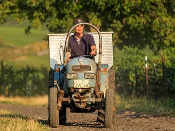 A tractor is driving over a dusty dirt road.
