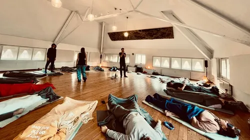 People lying on mats in large room.