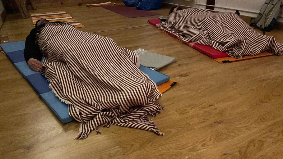 Menschen schlafen auf Matten in einem Raum.