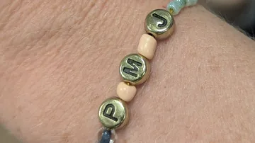 Armband mit Metall-Buchstaben-Perlen am Handgelenk.