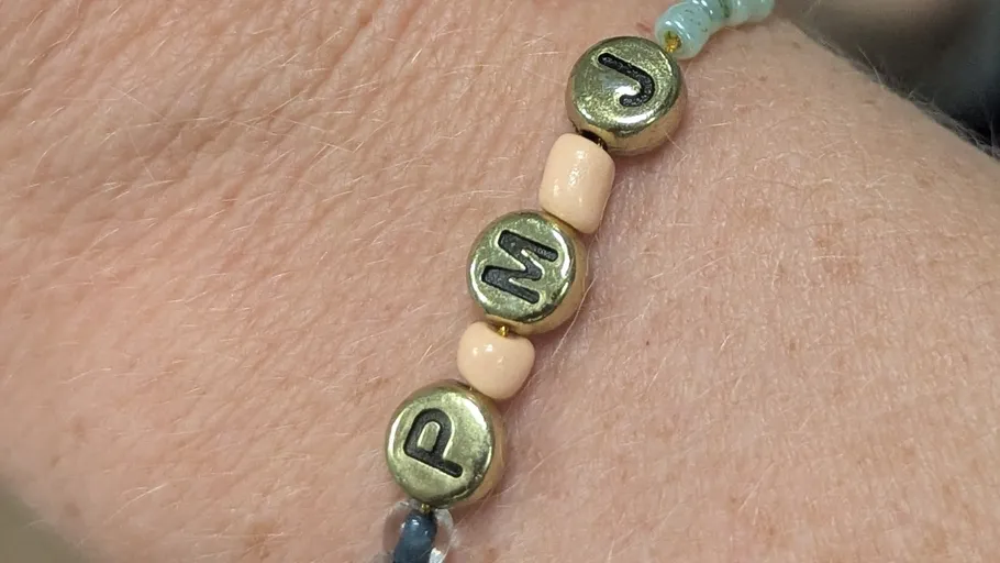Armband mit Metall-Buchstaben-Perlen am Handgelenk.