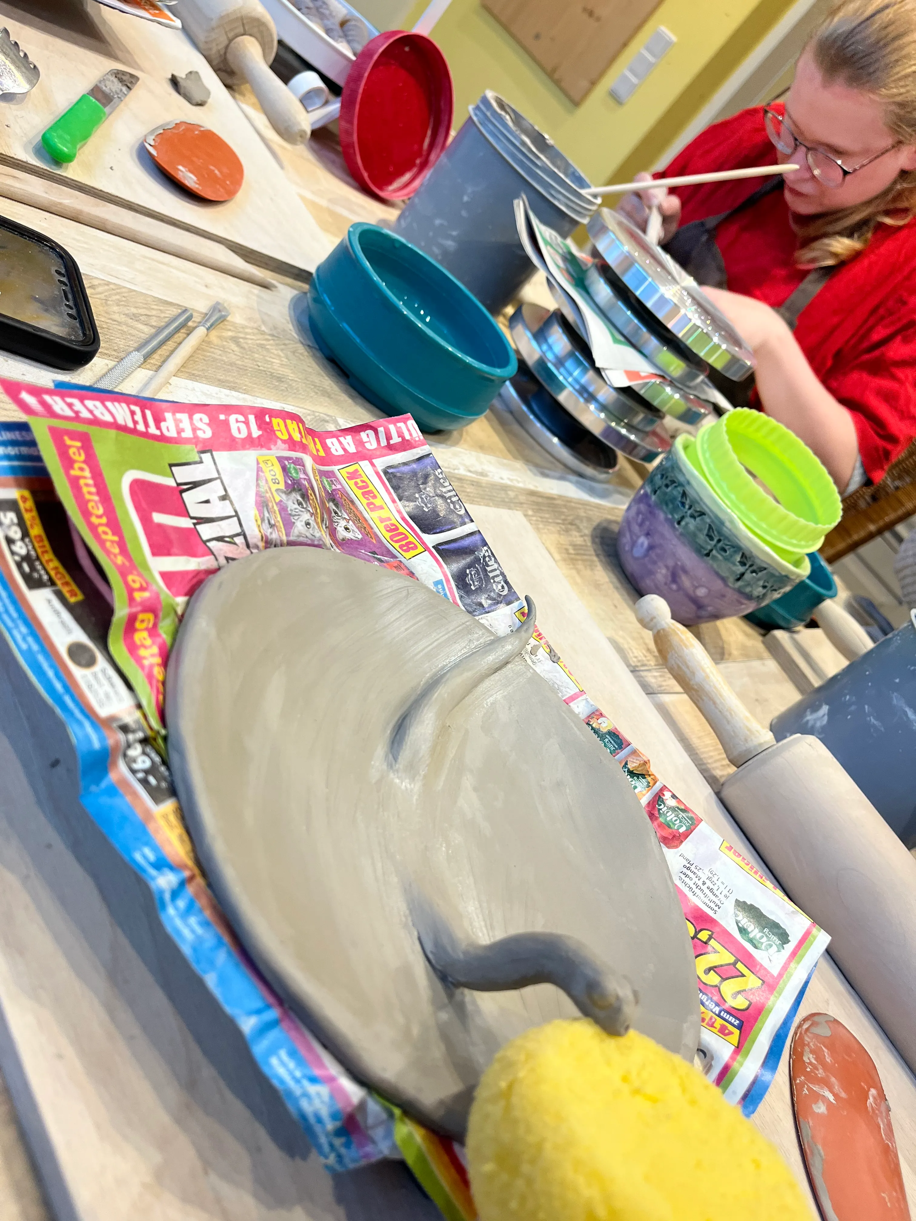 Person bemalt Keramik an einem Tisch.