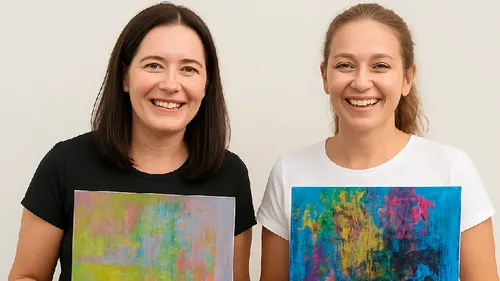 Two women holding abstract paintings indoors.