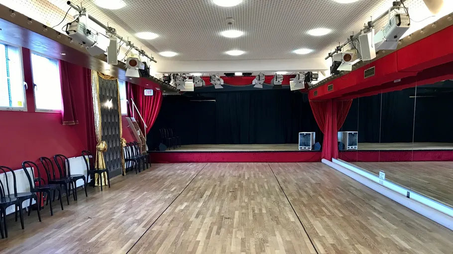 Leeres Tanzstudio mit Holzboden, Spiegeln, Stühlen.
