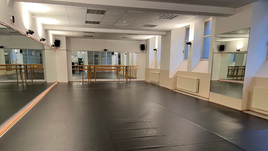 Empty dance studio with mirrors and ballet barres.