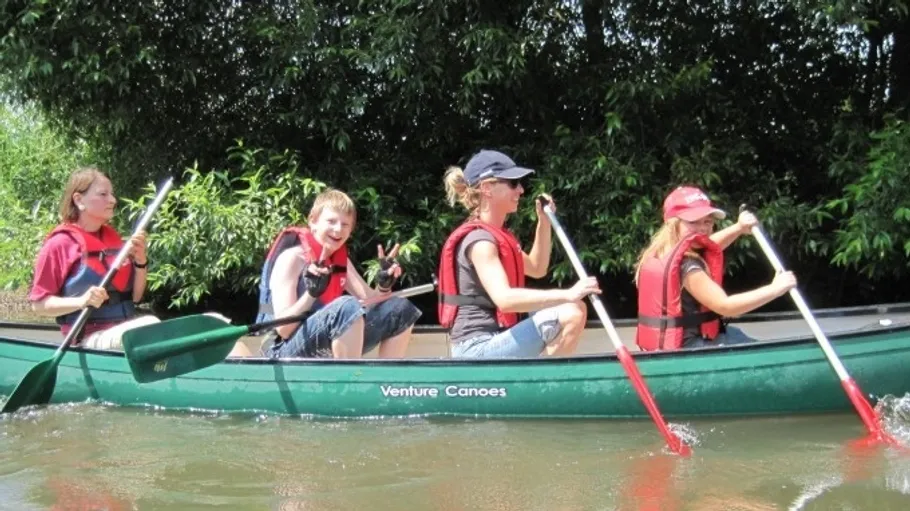 Four people paddling a canoe on a river.