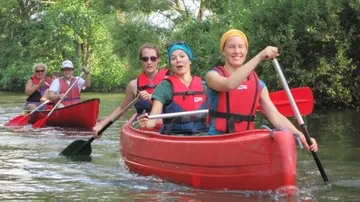 Group paddling red canoes on a river.