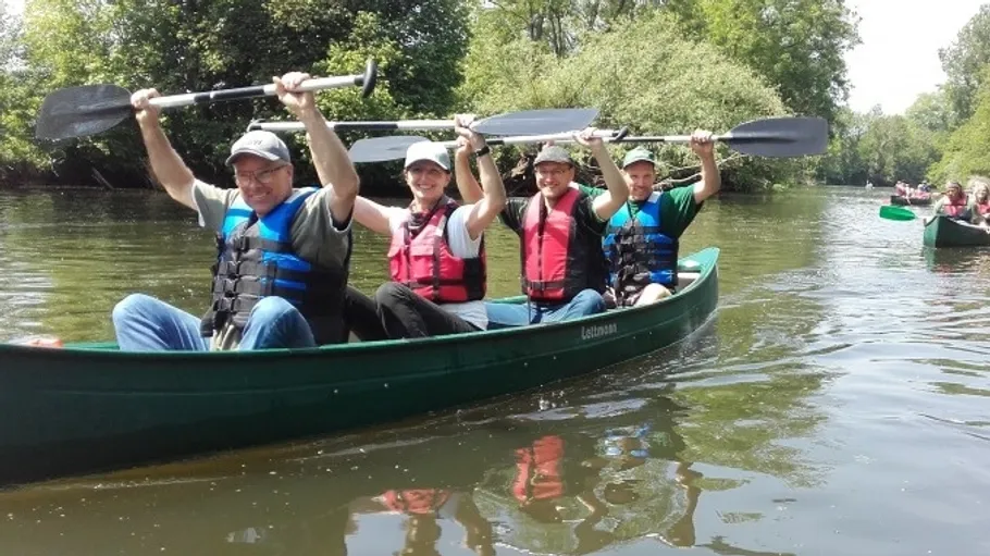 Four people paddling in a canoe on river.