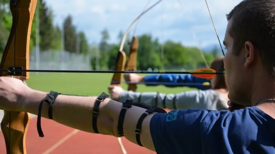 People aiming bows at targets outdoors.