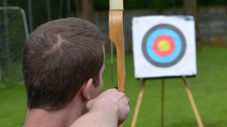 Archer aiming at a target outdoors.