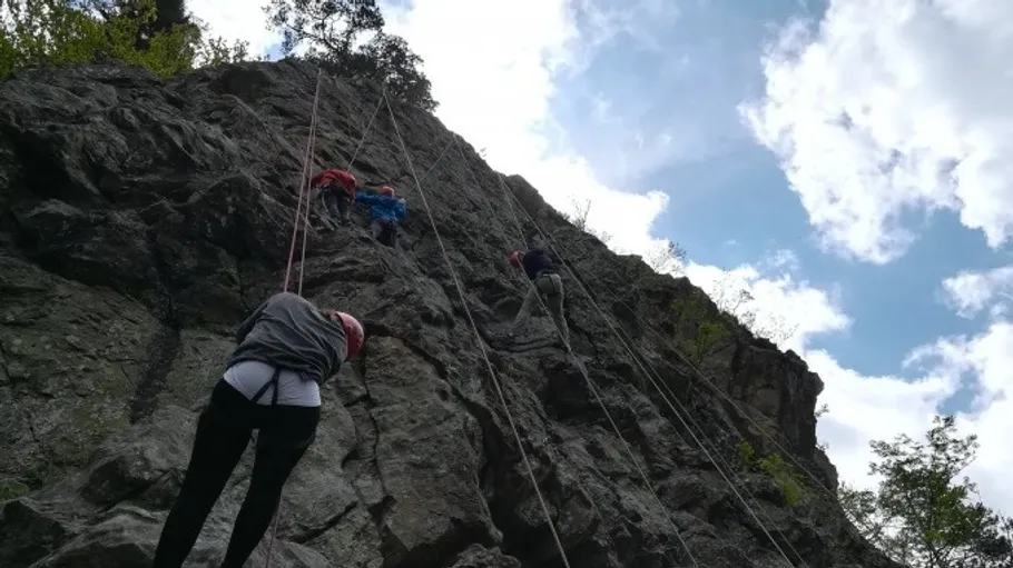 Menschen klettern an einer steilen Felswand im Freien.