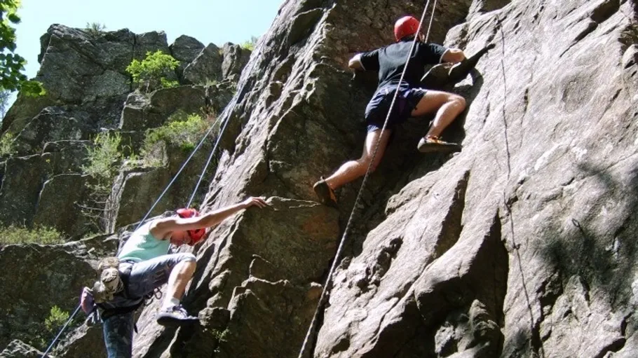 Two people rock climbing on a steep cliff.