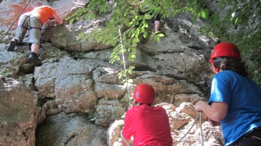 Three climbers ascending a rock wall outdoors.