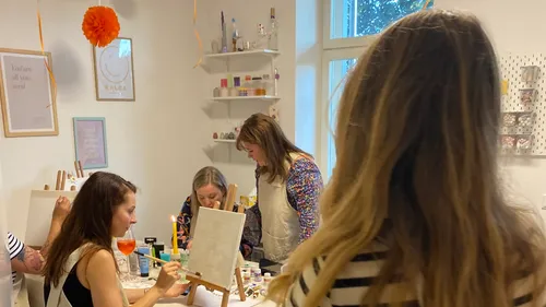 Women painting in a cozy, decorated room.