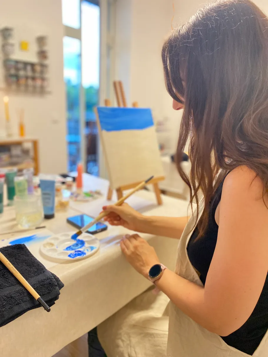 Woman painting on canvas in art studio.