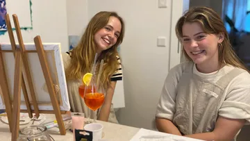 Two women smiling while sitting at table.