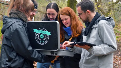 Gruppe untersucht Laptop im Wald draußen.