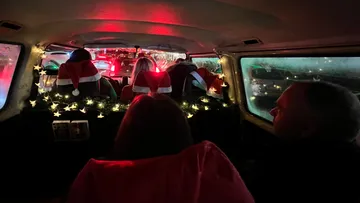 Leute tragen Weihnachtsmützen in einem geschmückten Van.