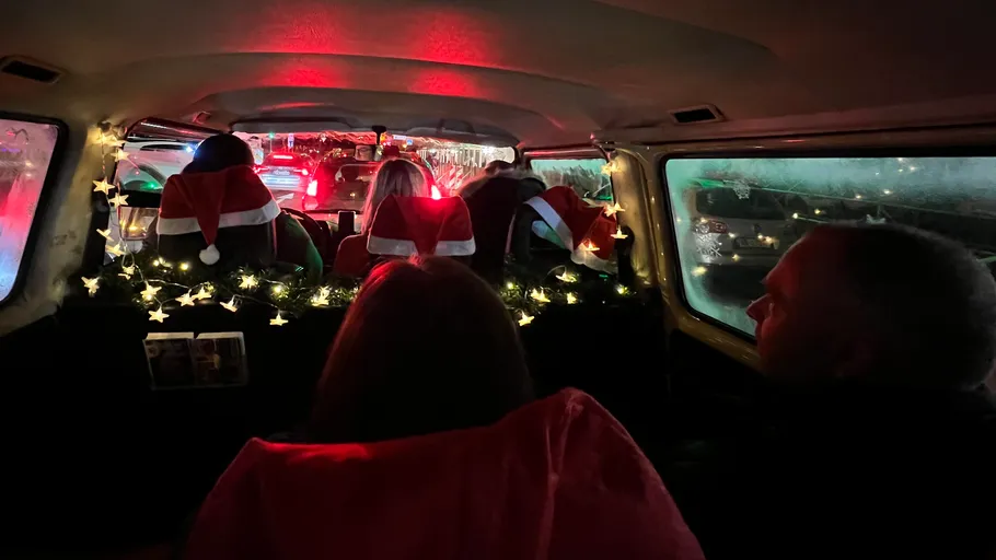 People wearing Santa hats inside a decorated van.
