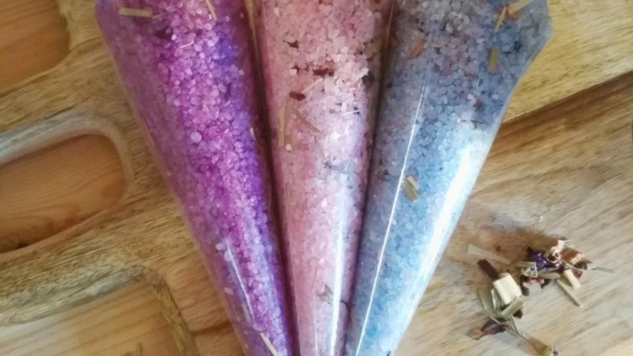Bunte Badesalze in Plastiktüten auf Holz.
