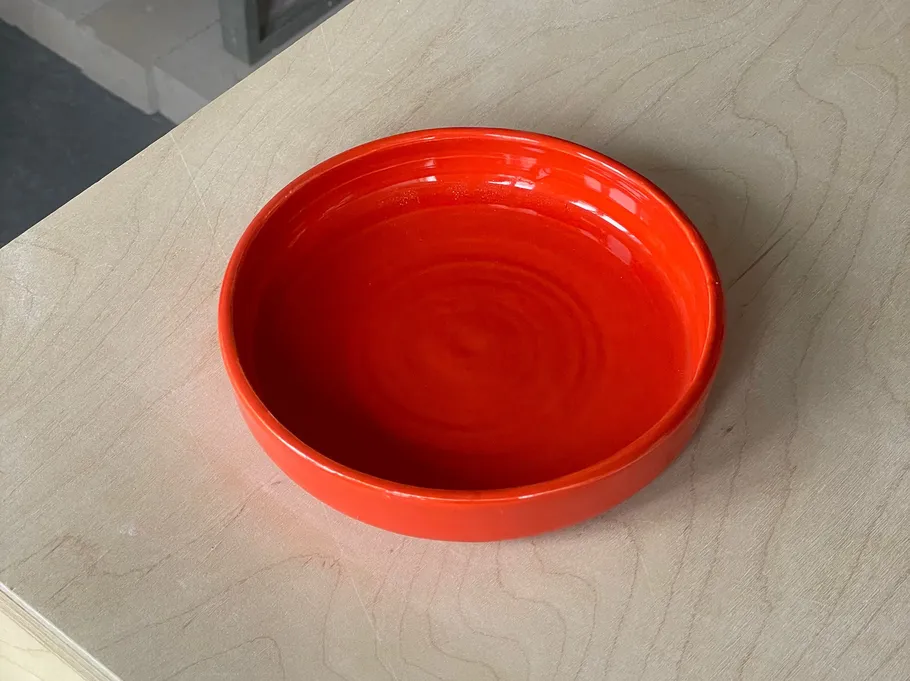 Red ceramic bowl on wooden surface.