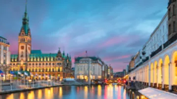 Historic buildings reflected in city canal at dusk.