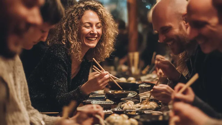 Group enjoying dinner with chopsticks in restaurant.
