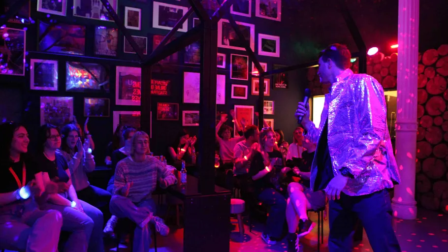 Performer in shiny jacket entertaining seated audience.