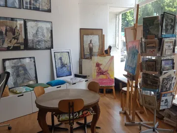Kunstgalerie mit Bildern, Möbeln und Aussicht auf die Straße.