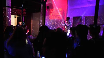 Performer sings on stage, colorful lights.