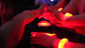 Hands reaching for glowing red button.