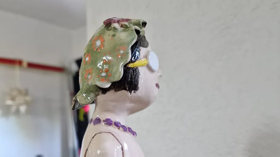 Keramikfigur mit Kopftuch in einem Raum.