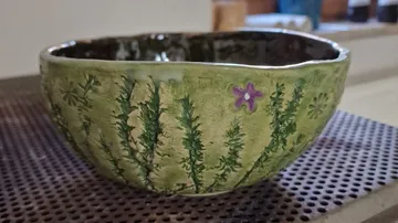 Ceramic bowl with leafy design on mat.