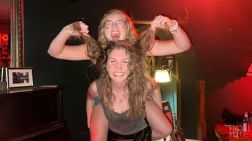 Zwei Frauen haben Spaß in einem schwach beleuchteten Raum.