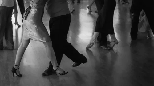 Couple dancing tango on a wooden floor.