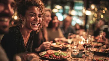 Lächelnde Frau isst mit Freunden im Restaurant.