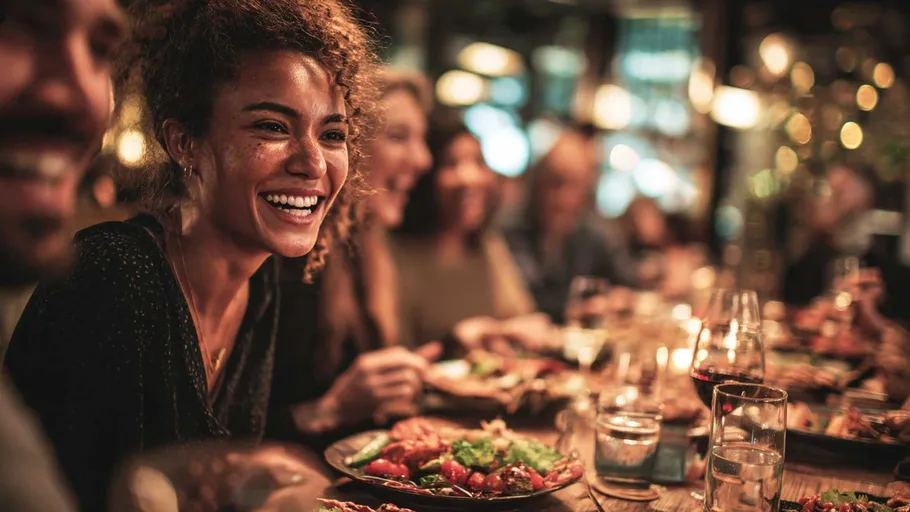 Lächelnde Frau isst mit Freunden im Restaurant.