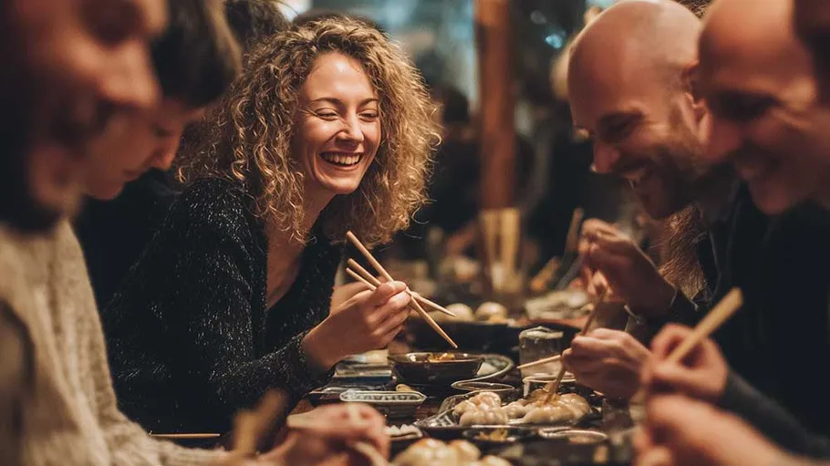Group joyfully eating with chopsticks in restaurant.
