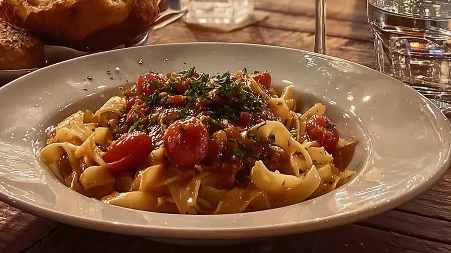 Pasta with tomatoes on a wooden table.