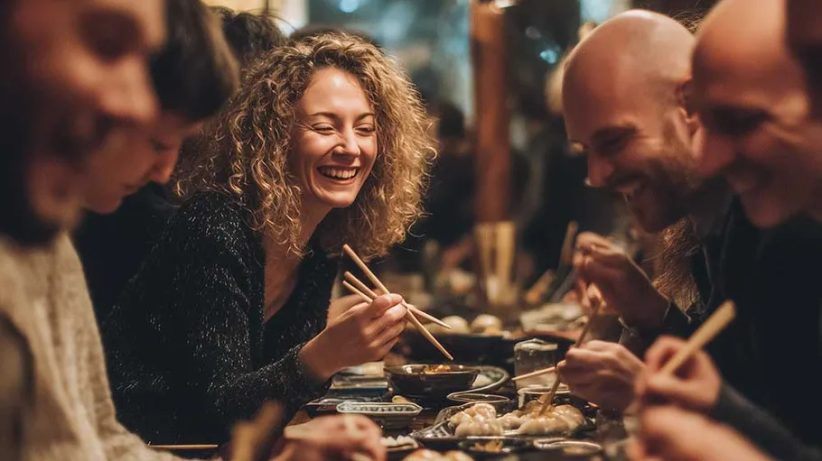 People enjoying meal with chopsticks in a restaurant.