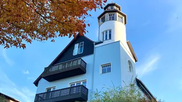House with lighthouse tower, sunny sky.