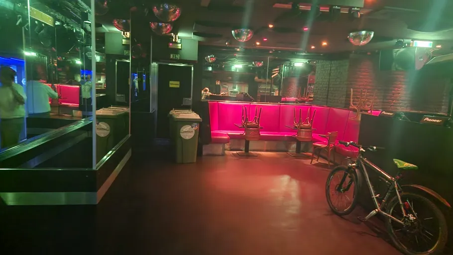 Leerer Nachtclub mit pinken Sitzgruppen und Fahrrad.