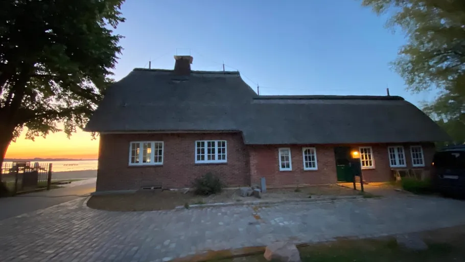 Backsteinhaus mit Reetdach bei Sonnenuntergang.